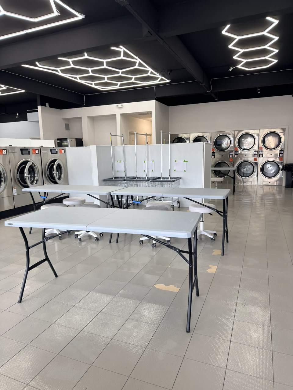 Crew’s Coin Laundromat interior with stainless-steel machines and hexagonal ceiling lights
